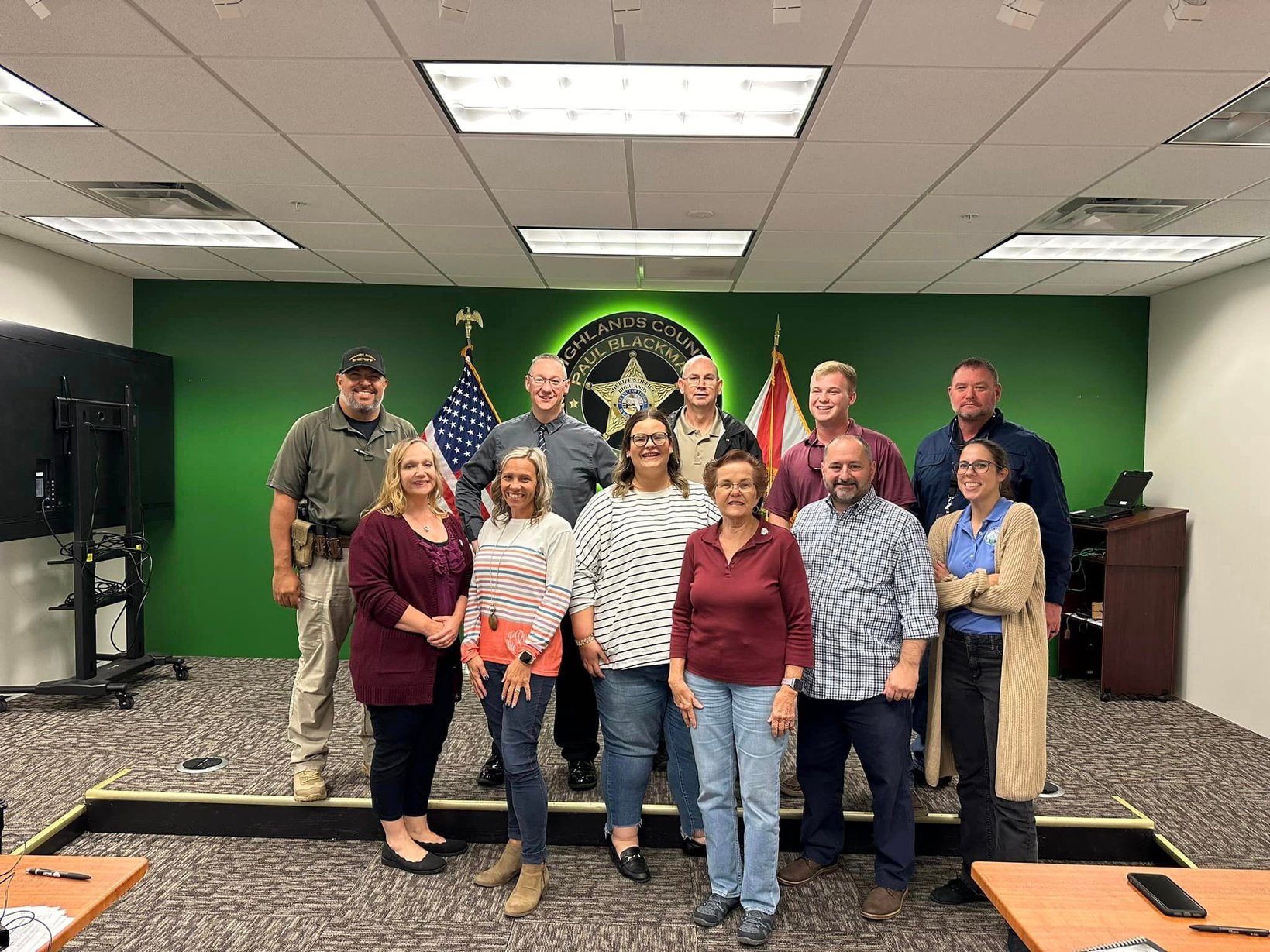 Small group standing in front of Sheriff's Office logo