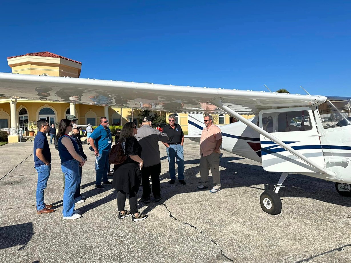 Class member standing by small airplane